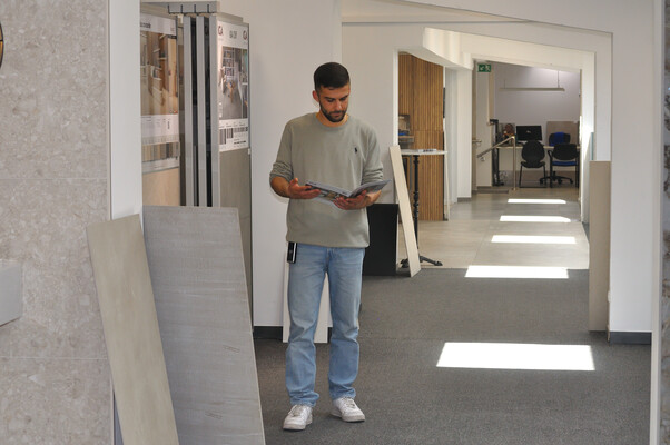 Blick in die Ausstellung mit einem Mitarbeiter, der einen Katalog, den Sie bei uns bekommen, in der Hand hält.